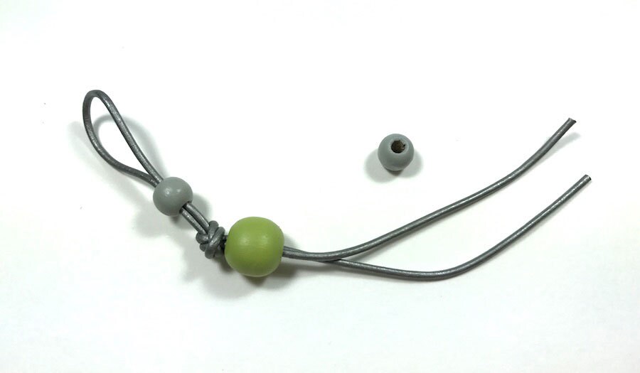 Painted beads threaded with a folded gray cord.