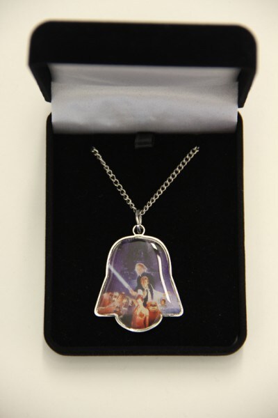 A necklace with a pendant containing poster art from Star Wars: Return of the Jedi, shaped like Darth Vader's helmet.