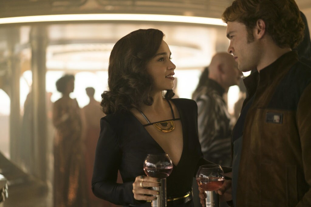 Qi'ra talks to Han Solo mingle with drinks at a bar.