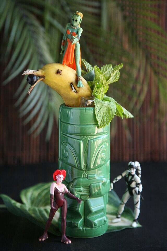 A green tiki mug designed like a Stormtrooper decorated with Star Wars action figures.