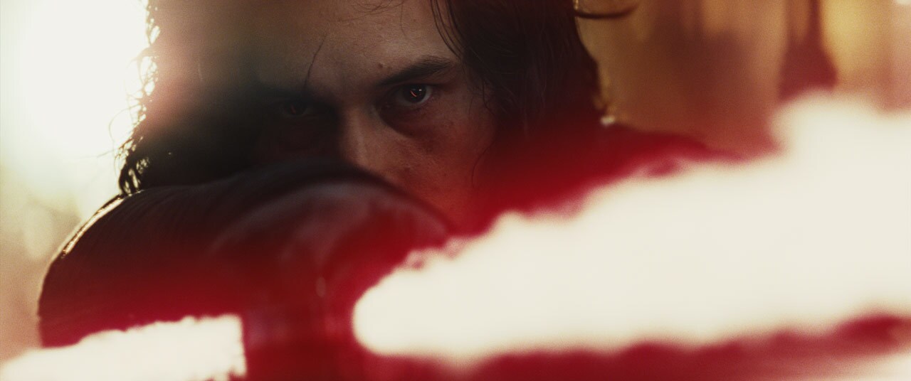 Kylo Ren gives a menacing look as he extends his lightsaber in The Last Jedi.