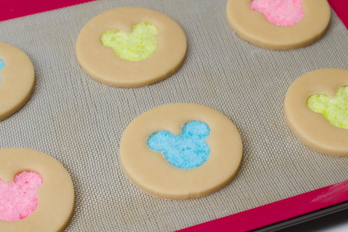 Cookies with brightly colored Mickey Mouse heads made from crushed hard candy in the middle.