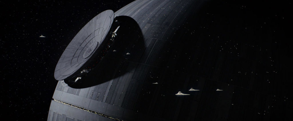 Star Destroyers look small as they fly in front of the Death Star.