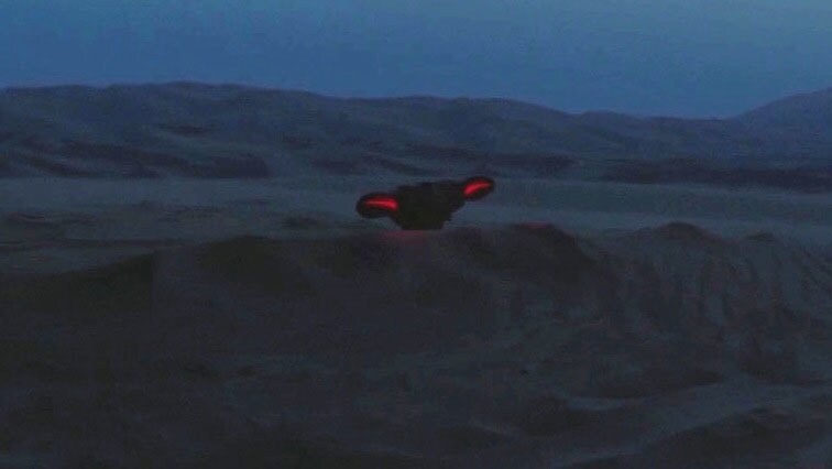 A Nightwatcher worm with glowing red eyes peers up over a sand dune.