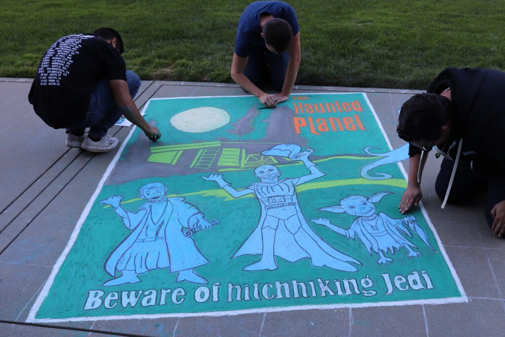 Three artists work on sidewalk chalk art inspired by Disneyland's Haunted Mansion attraction poster, with Obi-Wan Kenobi, Darth Vader, and Yoda as the Hitchhiking Jedi.