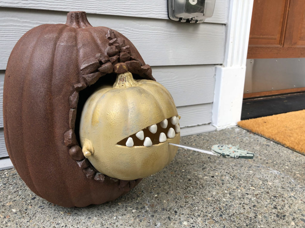 A carved pumpkin sculpture made to look like a toothed space slug pursuing the Millennium Falcon.