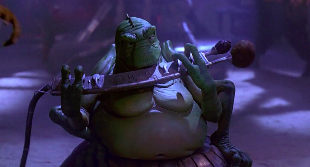 A green creature from plays an instrument in Jabba's Palace.