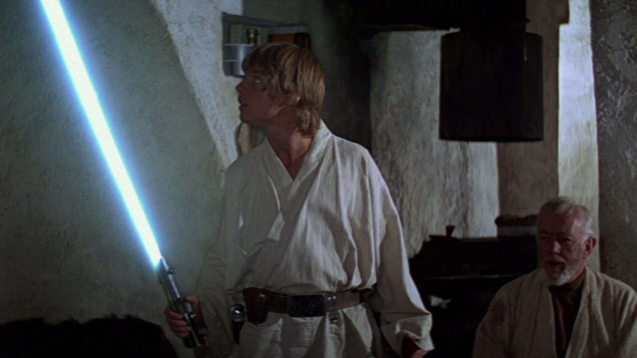 Luke tries using a lightsaber for the first time while Obi-Wan looks on in A New Hope.