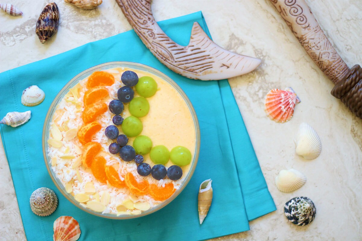 A tropical-inspired smoothie bowl topped with green grapes, blueberries, and tangerine sections.