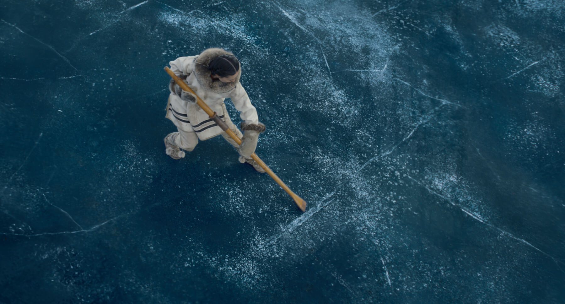 A woman standing on a frozen body of water with a crack in it from the movie "The Call of the Wild"