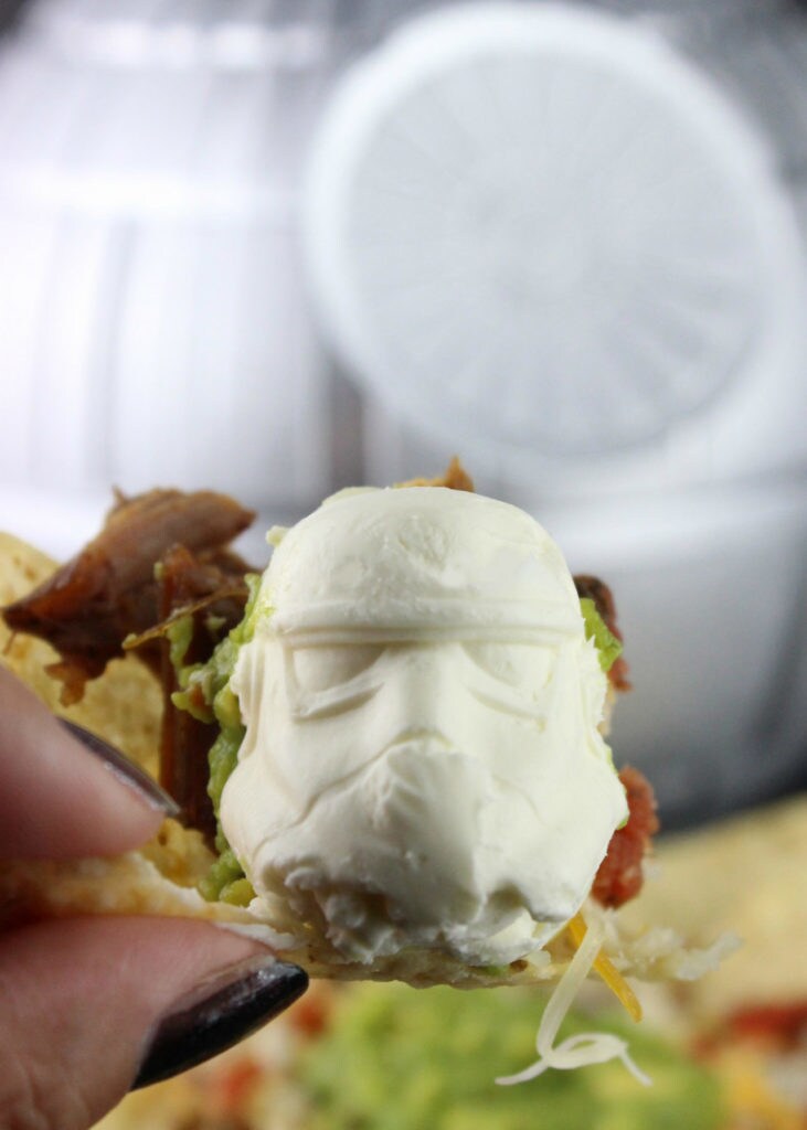 A dollop of sour cream in the shape of a Stormtrooper helmet on a loaded nacho.