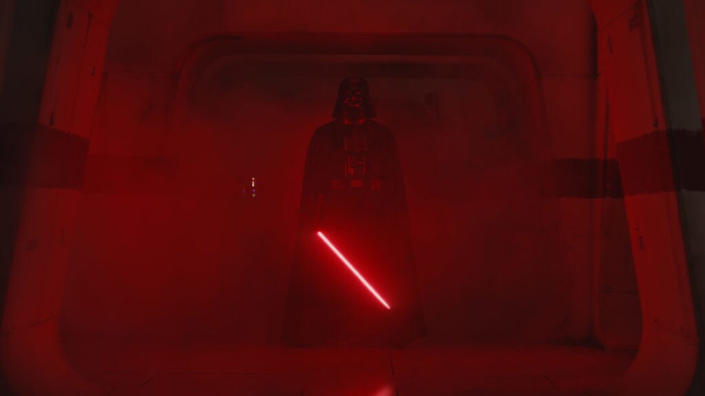 Darth Vader stands in a smokey corridor, illuminated by his red lightsaber, in Rogue One: A Star Wars Story.