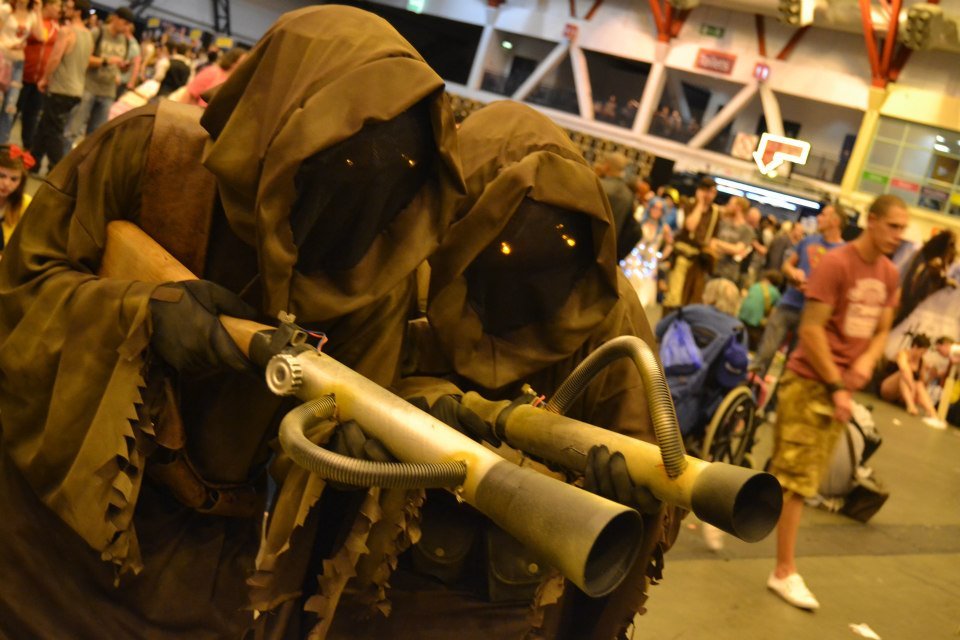 Fans in Jawa costumes aim their blasters.