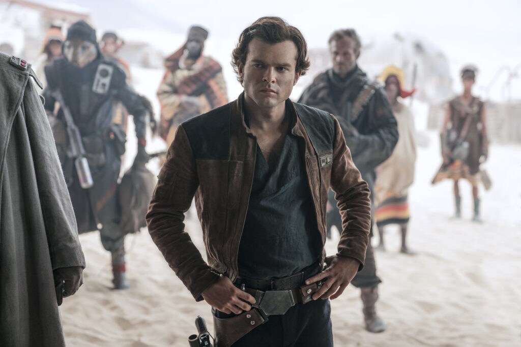 Han Solo stands with his hands on his hips among a group of outlanders in Solo: A Star Wars Story.