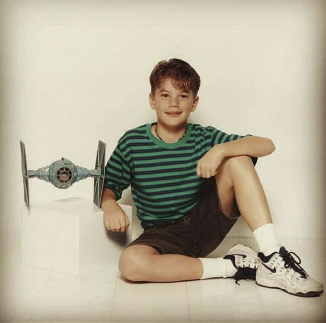 Dustin as a child posing with a TIE fighter