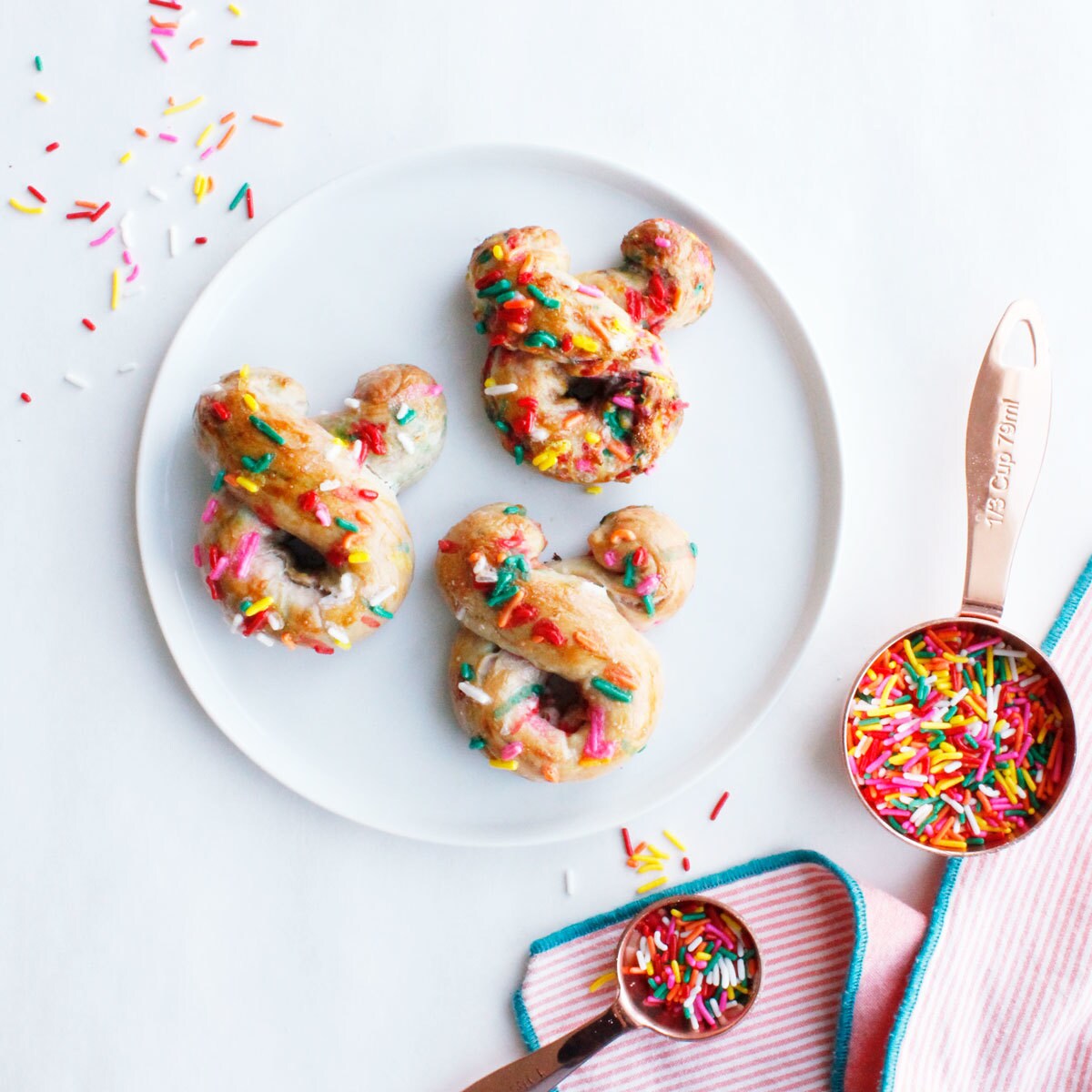 Mickey Mouse shaped pretzels decorated with sprinkles.