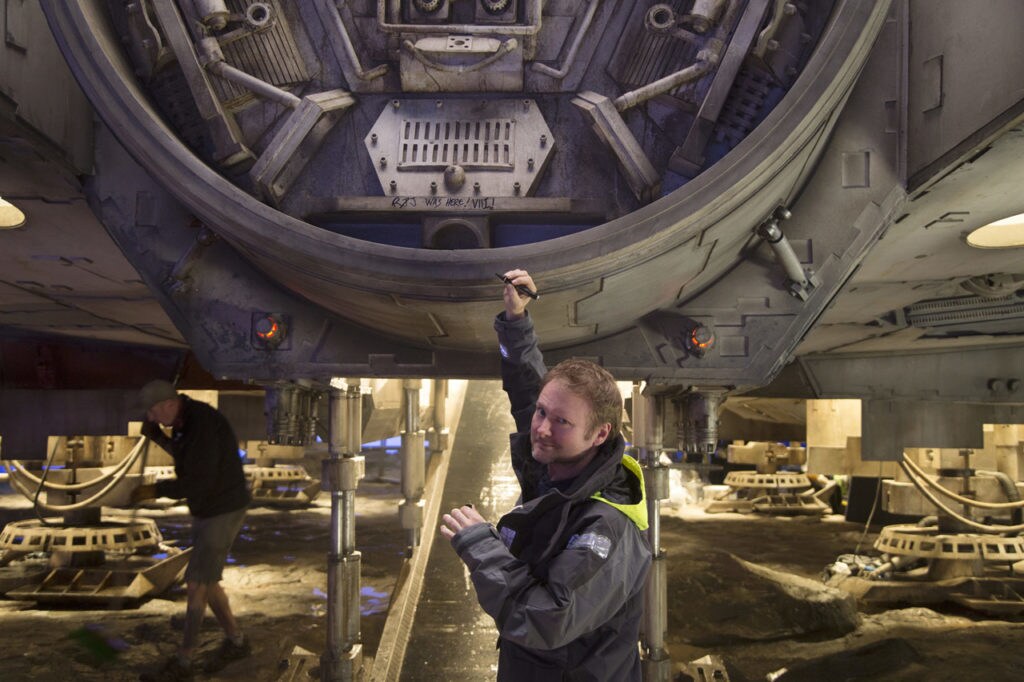 Director Rian Johnson looks back at the camera after writing his initials on the Millennium Falcon, on the set of The Last Jedi.