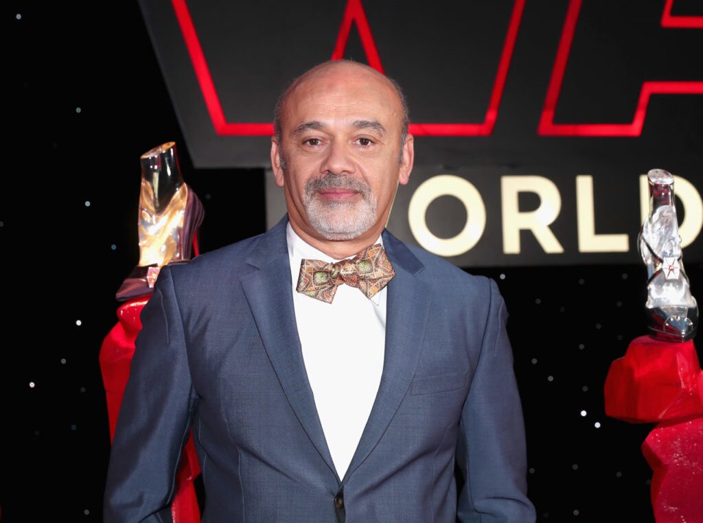 Fashion designer Christian Louboutin poses in front of a display of Star Wars: The Last Jedi-inspired shoes he created.