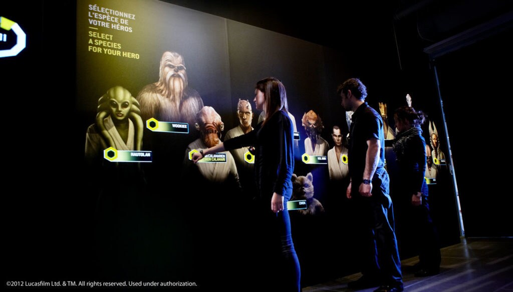Visitors at the Star Wars Identities exhibit choose the species of their hero on an interactive wall with various characters.
