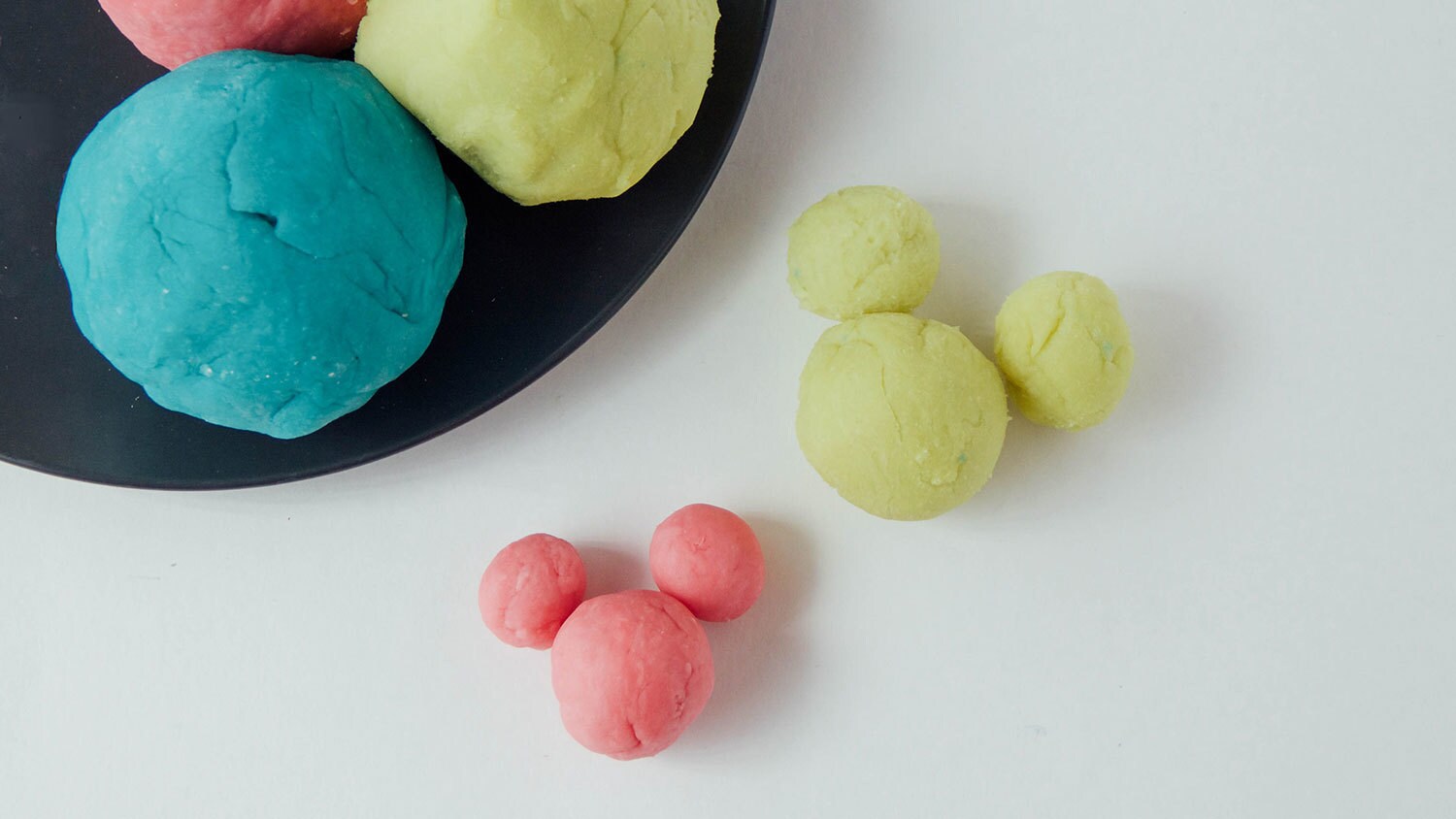 Different colored homemade sensory dough balls. Some are shaped like Mickey Mouse.