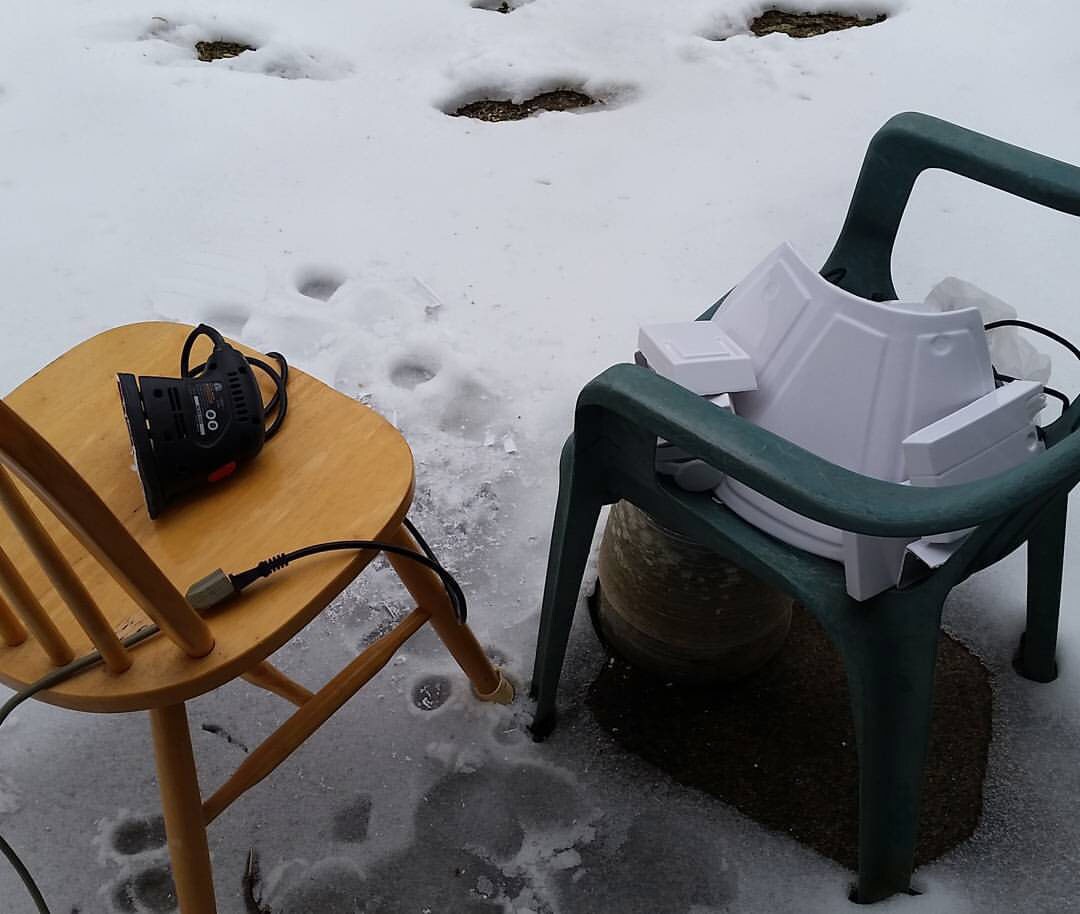 A sander sits on a chair next to a costume stormtrooper armor outside in the snow.