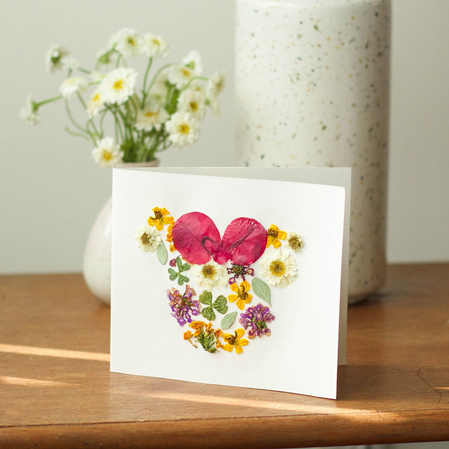A homemade card featuring pressed flowers in the shape of Minnie Mouse.