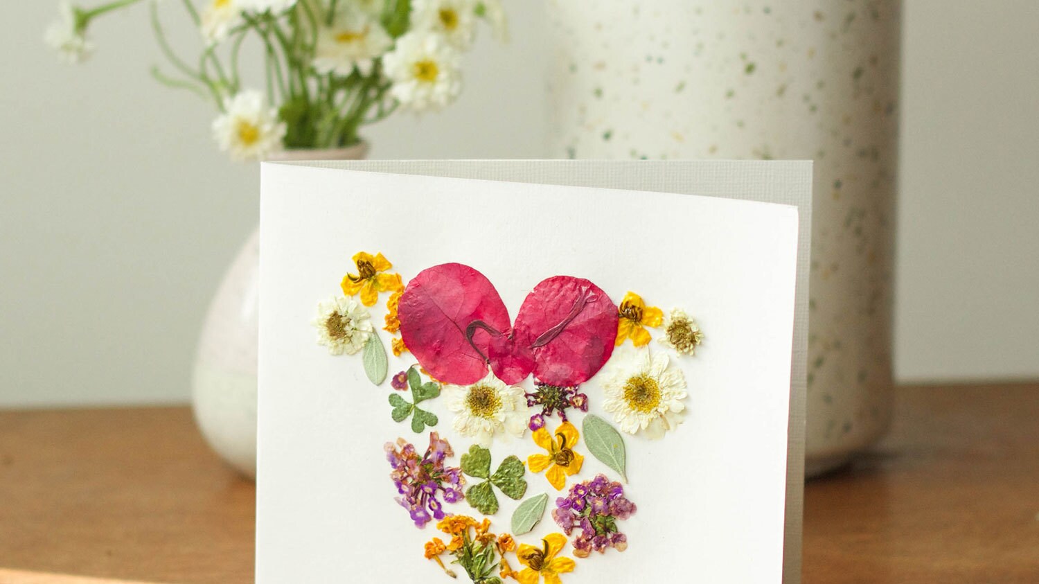 A homemade card featuring pressed flowers in the shape of Minnie Mouse.