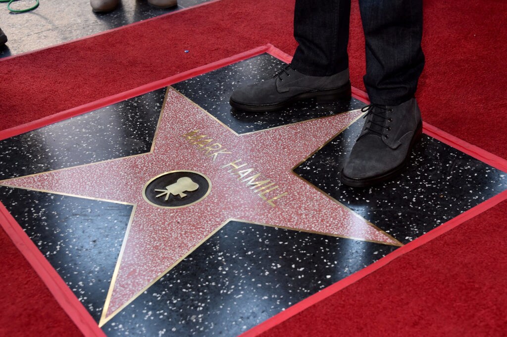 Mark Hamill stands in front of his star on the Hollywood Walk of Fame.