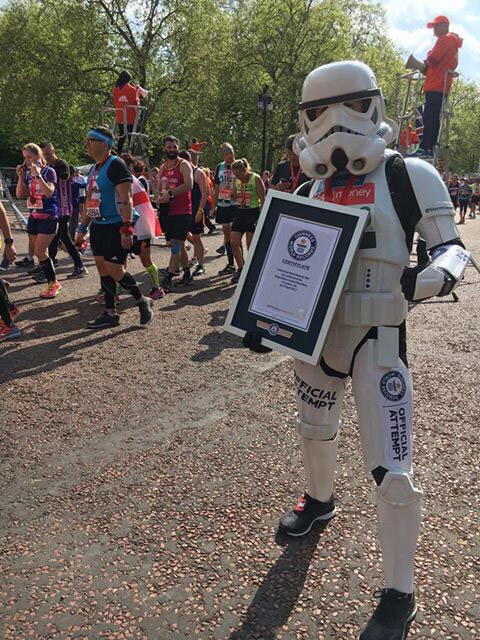 Royal Air Force officer Jez Allinson dressed as a stormtrooper holds a framed certificate acknowledging his accomplishments after completing the London Marathon.