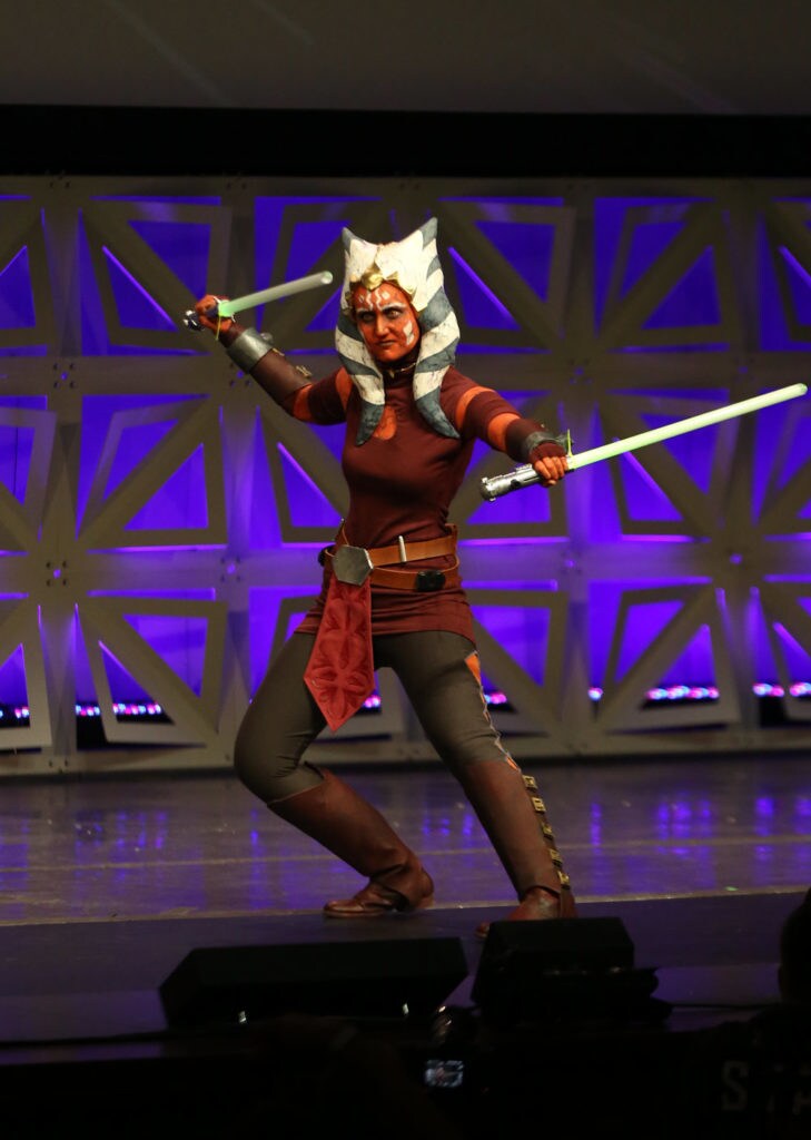 An Ahsoka Tano cosplayer brandishes her lightsabers.