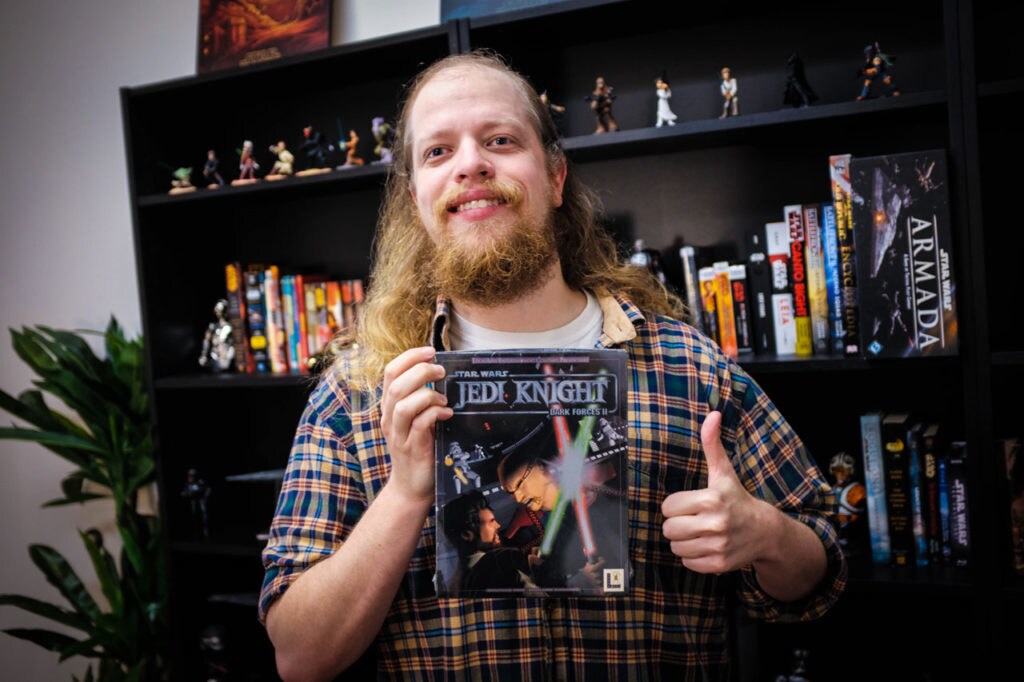 A member of the Lucasfilm Games Team holds up a copy of Dark Forces II: Jedi Knight.