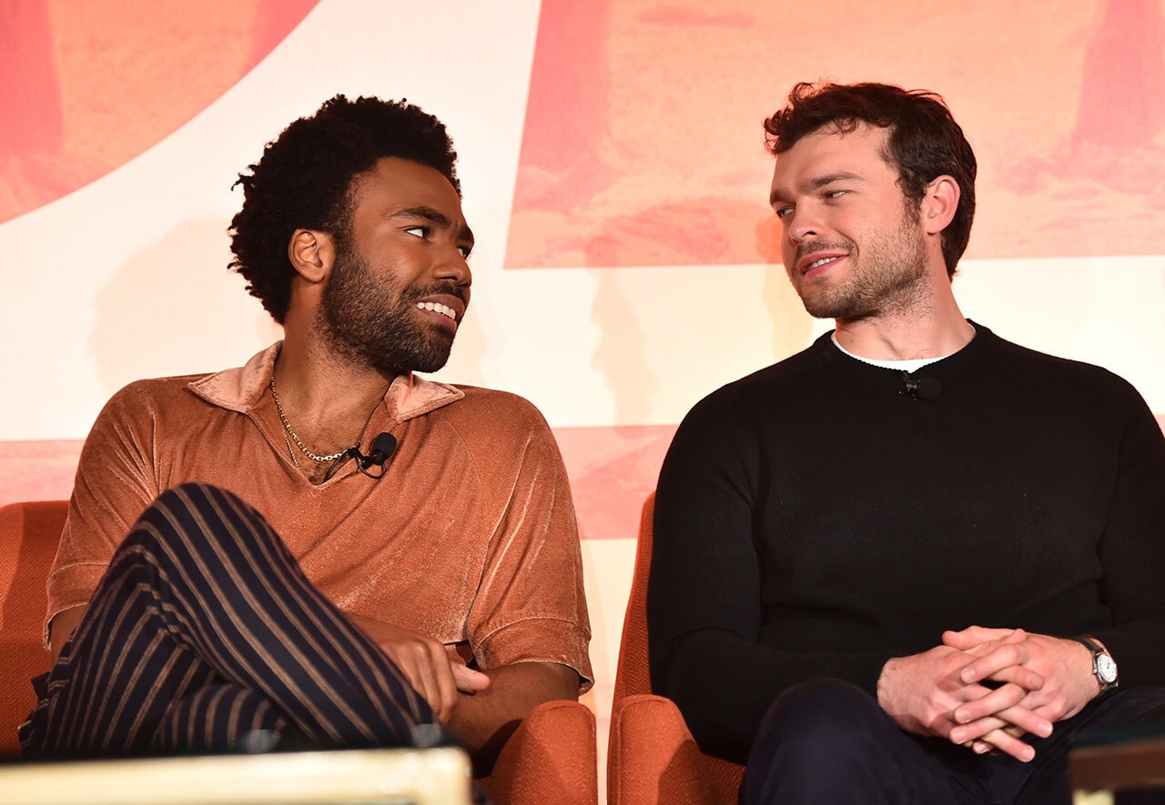 Donald Glover, and Alden Ehrenreich look at each other while speaking on stage at a press event for Solo: A Star Wars Story.