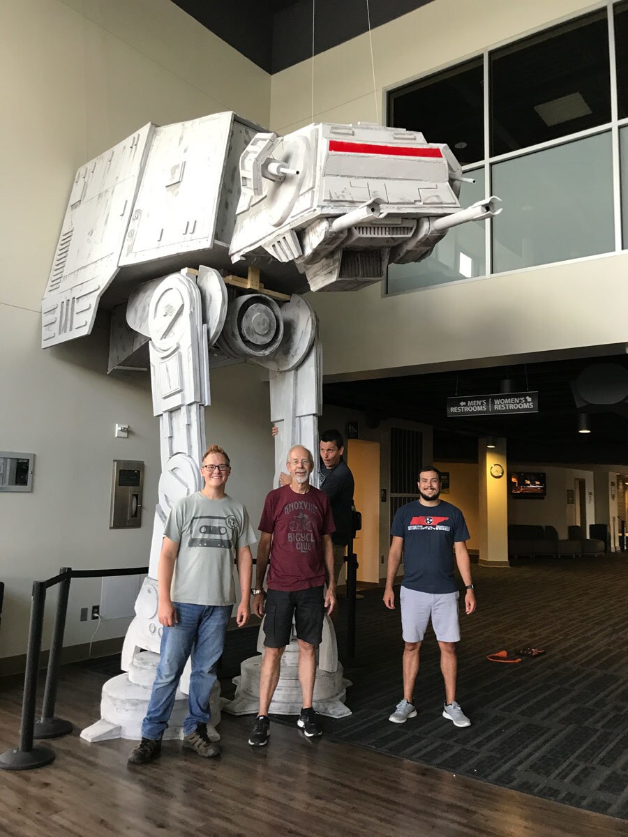 A small group poses in front of a 17-foot tall AT-AT created by a Star Wars fan.
