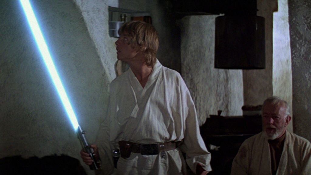 Luke tries using a lightsaber for the first time while Obi-Wan looks on in A New Hope.