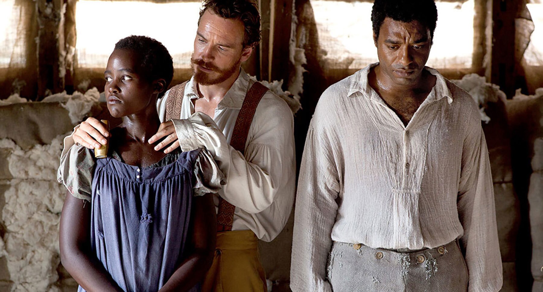 Actors Lupita Nyong'o (Patsy), Michael Fassbender (Edwin Epps), and Chiwetel Ejiofor (Solomon Northrup) standing in the film "12 Years A Slave"