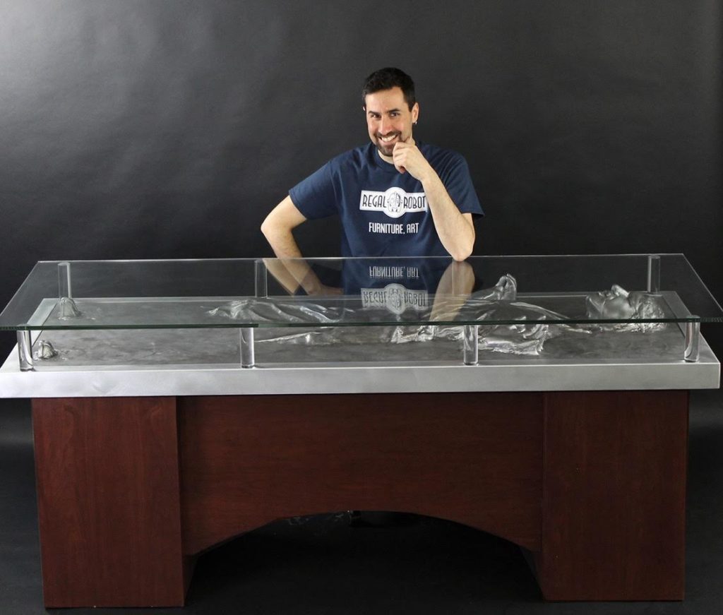 Tom Spina, founder of Regal Robot, sits behind the executive style desk he modeled after Han Solo in carbonite.
