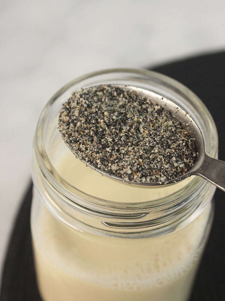 In a glass, stir together the oat milk, ground black sesame seeds, sugar, and vanilla, until combined