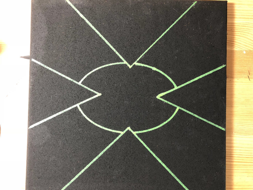 A black cork board with green lines and a green circle on it.