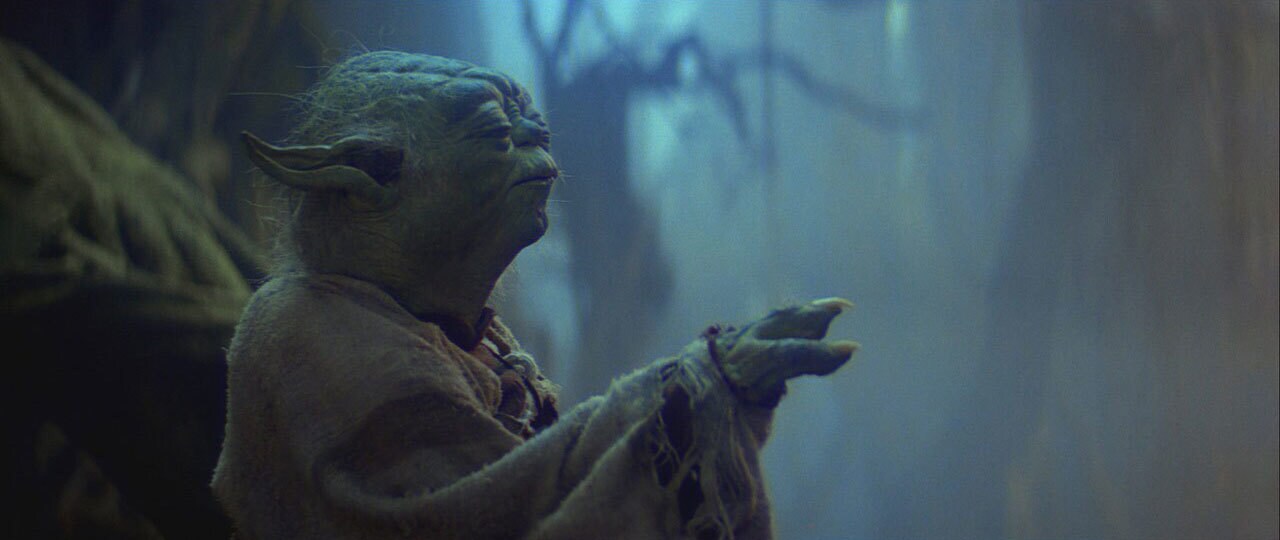 Yoda holds out his hand with his eyes closed, using the Force.