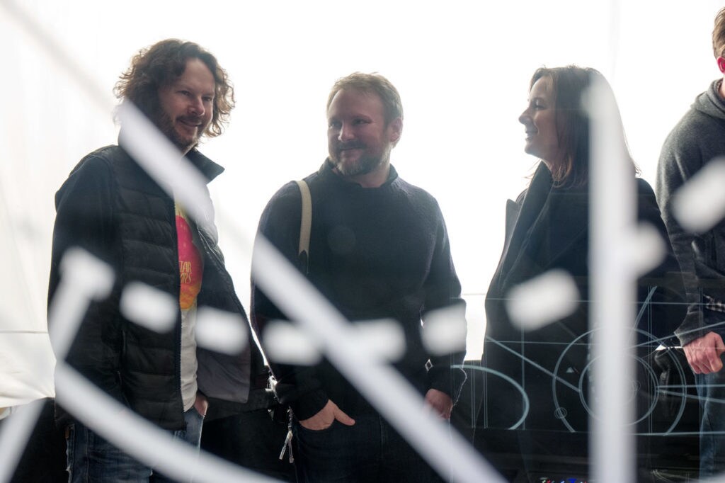 Director Rian Johnson and producers Ram Bergman and Kathleen Kennedy smile as they chat on the set of The Last Jedi.
