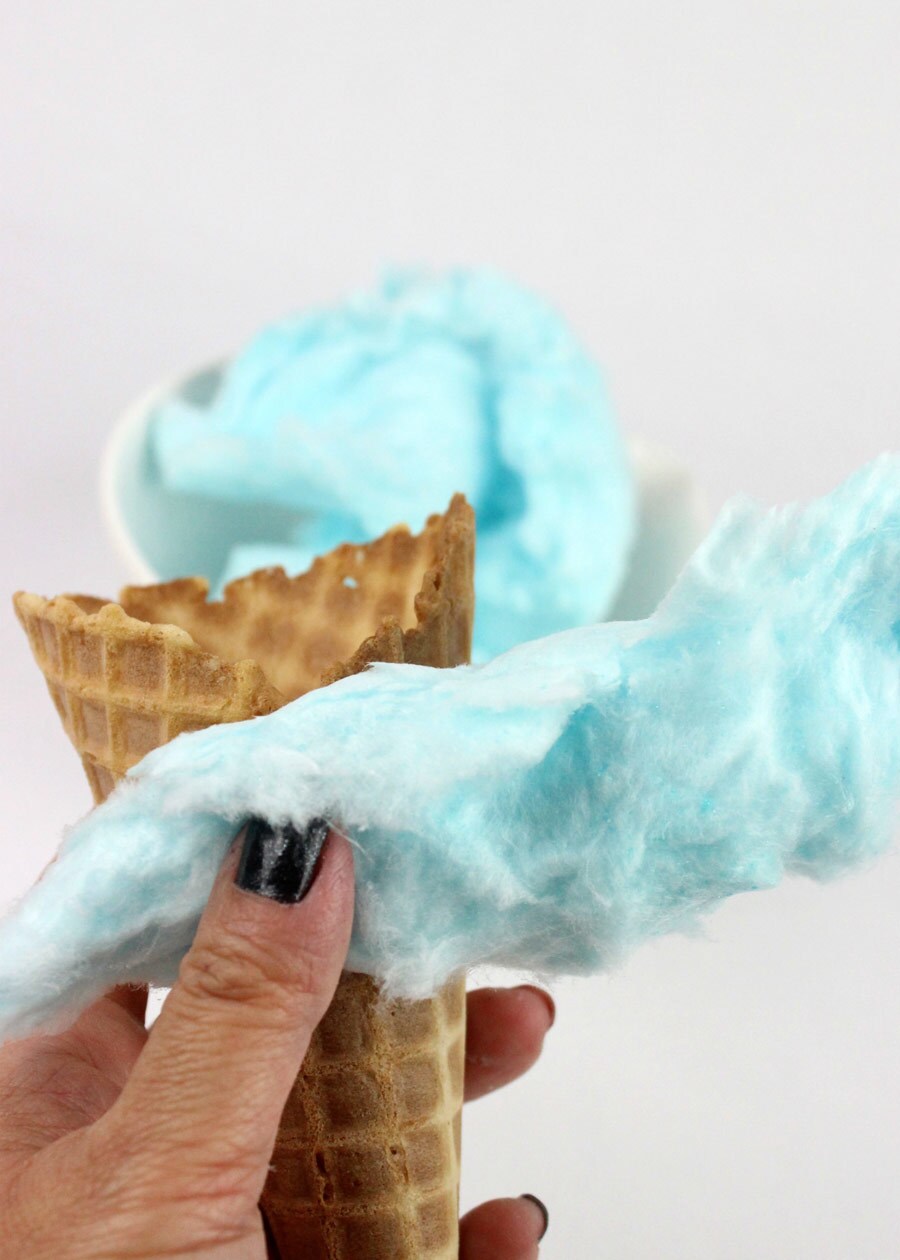 A waffle ice cream cone wrapped with decorative blue cotton candy.