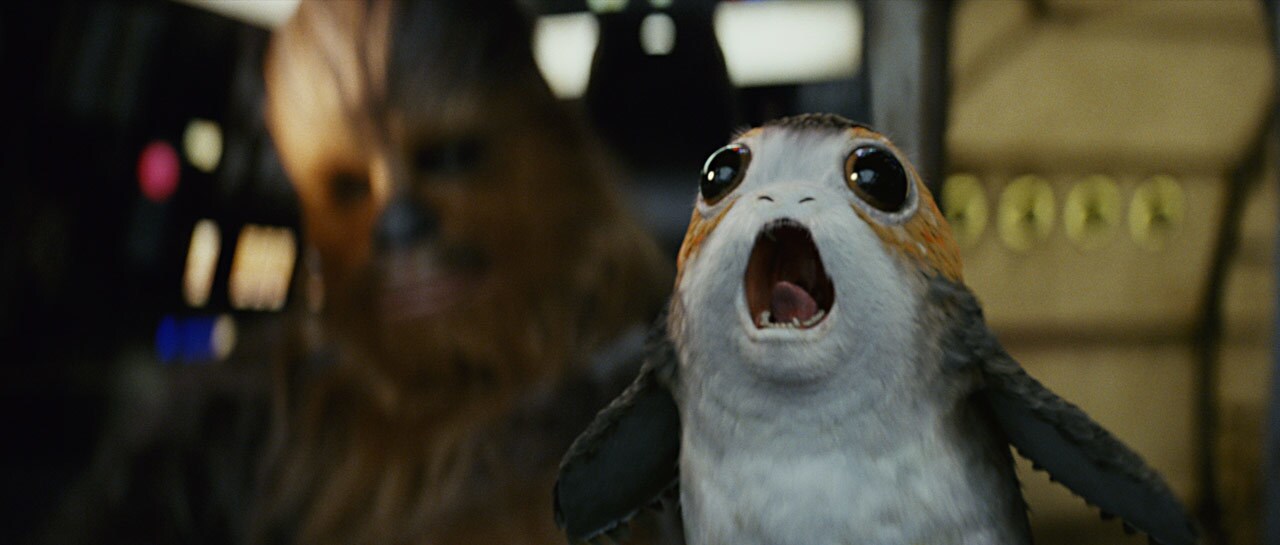 A porg screeches with Chewbacca behind him in The Last Jedi.