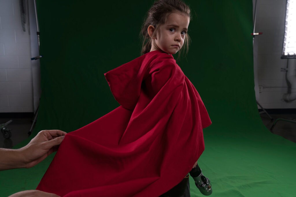Josh Rossi's daughter poses in front of a green screen.