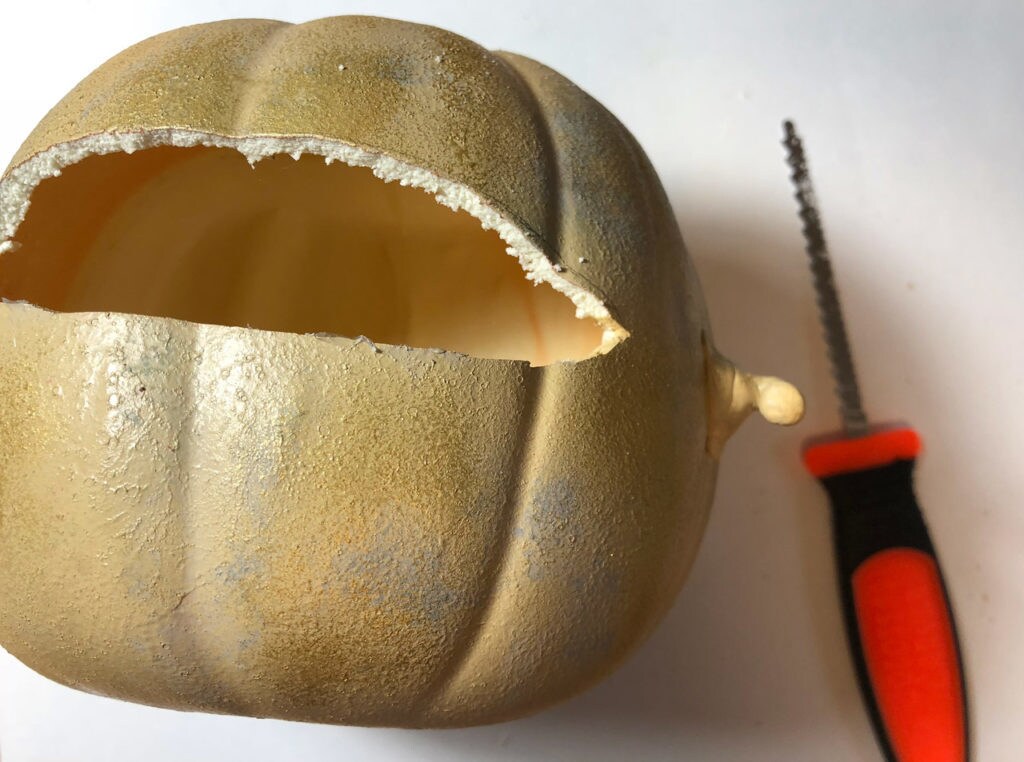 A carved and gutted pumpkin next to a carving knife.