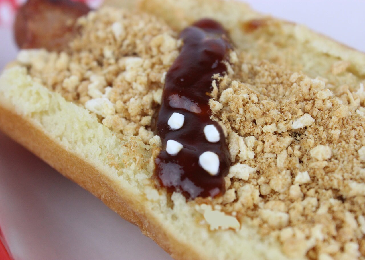 A strip of BBQ sauce on a breaded hot dog.