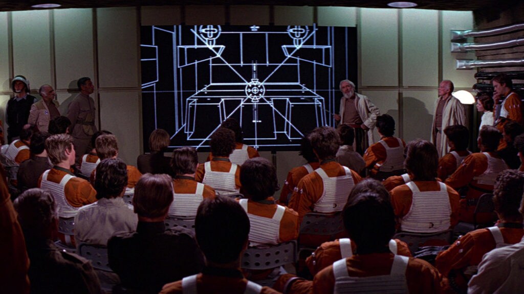 Rebe Alliance pilots sit in a briefing and examine diagrams of the Death Star.