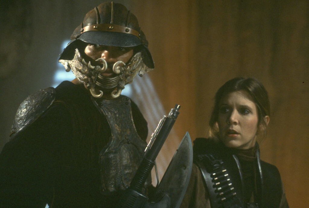 Leia and Lando, dressed as bounty hunters, stand inside Jabba's Palace in Return of the Jedi.