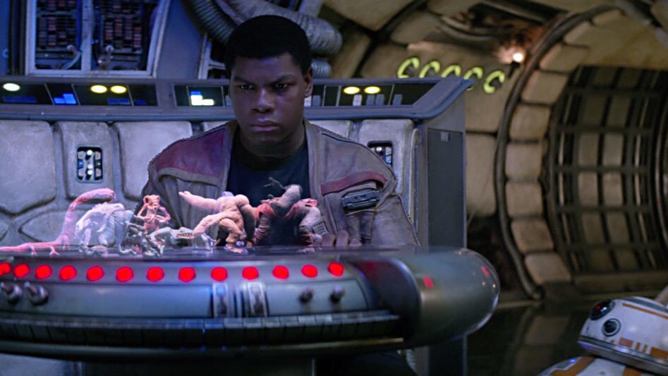 Finn stares at the holochess board on the Millennium Falcon, with BB-8 watching.
