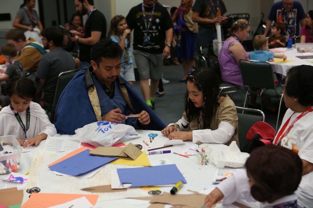 Adults and children craft together at the Star Wars Celebration Family area.