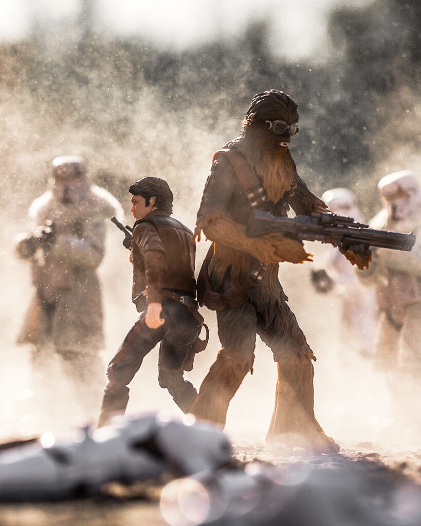 Action figures of Han Solo and Chewbacca stand back-to-back, surrounded by Imperial trooper figures.